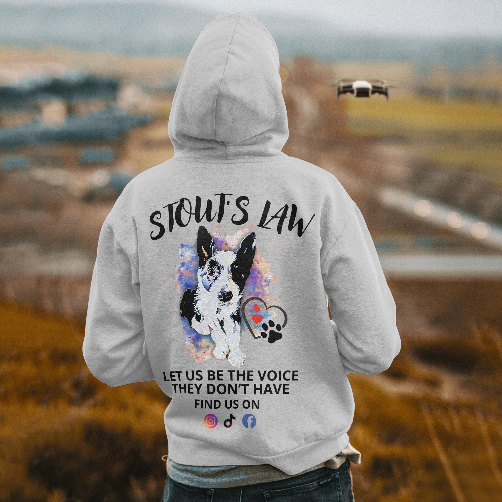 Person wearing a hoodie with 'STOUT'S LAW' text and dog illustration, standing in an outdoor setting.