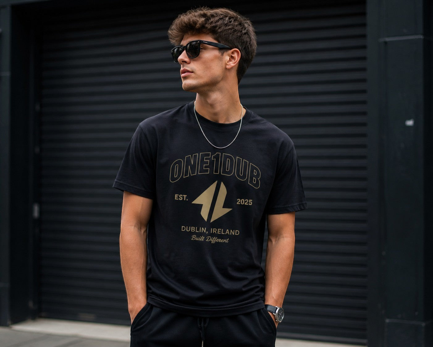 ONE1DUB black cotton t-shirt with gold graphic print, worn by a man with sunglasses and a silver chain.